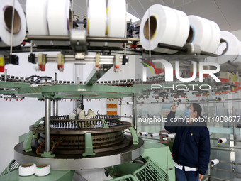 A worker is producing textile foreign trade products on a workshop production line at a spandex company workshop in the Lianyungang Economic...