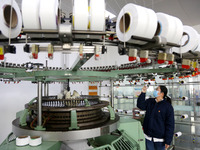 A worker is producing textile foreign trade products on a workshop production line at a spandex company workshop in the Lianyungang Economic...