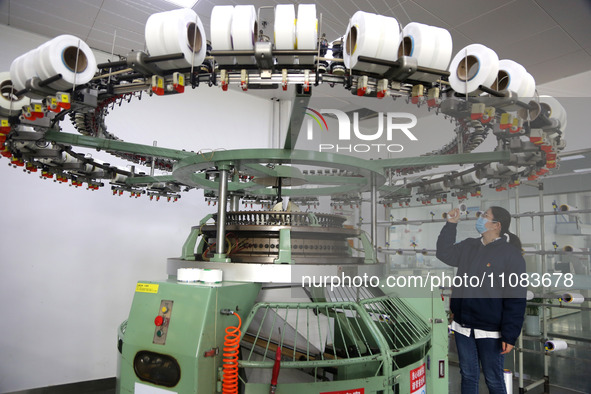 A worker is producing textile foreign trade products on a workshop production line at a spandex company workshop in the Lianyungang Economic...