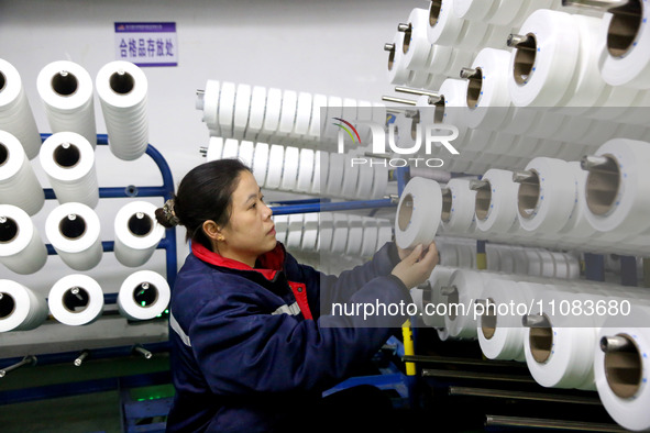 A worker is producing textile foreign trade products on a workshop production line at a spandex company workshop in the Lianyungang Economic...