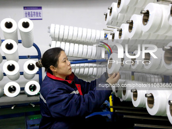 A worker is producing textile foreign trade products on a workshop production line at a spandex company workshop in the Lianyungang Economic...