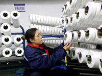 A worker is producing textile foreign trade products on a workshop production line at a spandex company workshop in the Lianyungang Economic...