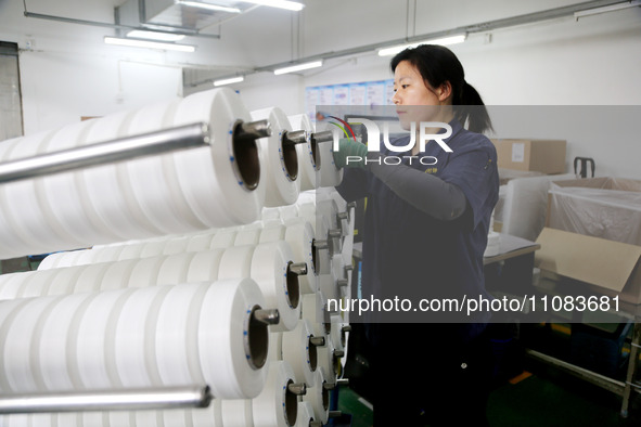 A worker is producing textile foreign trade products on a workshop production line at a spandex company workshop in the Lianyungang Economic...