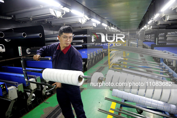 A worker is producing textile foreign trade products on a workshop production line at a spandex company workshop in the Lianyungang Economic...