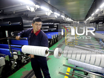 A worker is producing textile foreign trade products on a workshop production line at a spandex company workshop in the Lianyungang Economic...