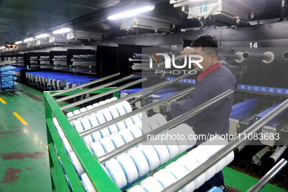 A worker is producing textile foreign trade products on a workshop production line at a spandex company workshop in the Lianyungang Economic...