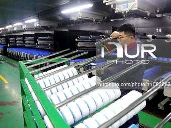 A worker is producing textile foreign trade products on a workshop production line at a spandex company workshop in the Lianyungang Economic...