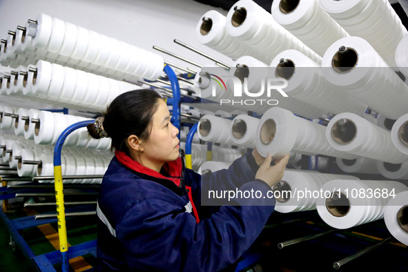 A worker is producing textile foreign trade products on a workshop production line at a spandex company workshop in the Lianyungang Economic...