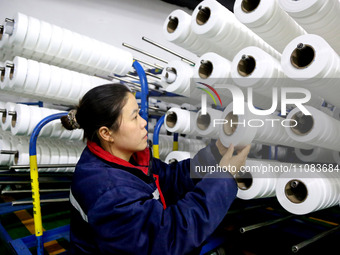 A worker is producing textile foreign trade products on a workshop production line at a spandex company workshop in the Lianyungang Economic...