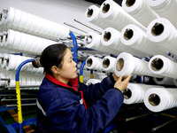 A worker is producing textile foreign trade products on a workshop production line at a spandex company workshop in the Lianyungang Economic...