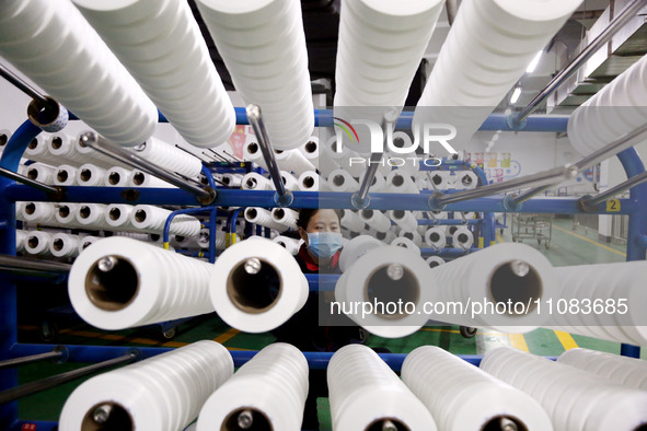 A worker is producing textile foreign trade products on a workshop production line at a spandex company workshop in the Lianyungang Economic...