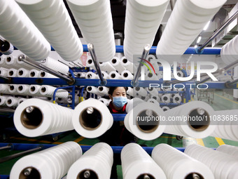 A worker is producing textile foreign trade products on a workshop production line at a spandex company workshop in the Lianyungang Economic...