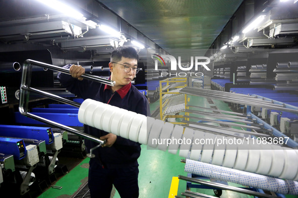 A worker is producing textile foreign trade products on a workshop production line at a spandex company workshop in the Lianyungang Economic...