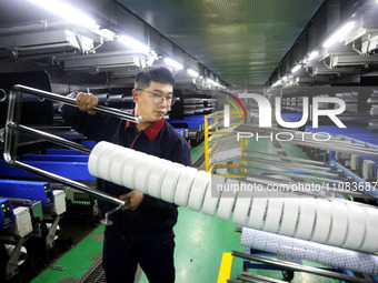 A worker is producing textile foreign trade products on a workshop production line at a spandex company workshop in the Lianyungang Economic...