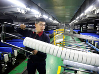 A worker is producing textile foreign trade products on a workshop production line at a spandex company workshop in the Lianyungang Economic...