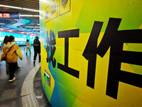 Passengers are walking past a light box advertising ''looking for jobs'' at Dawanglu Metro station in Beijing, China, on March 17, 2024. (