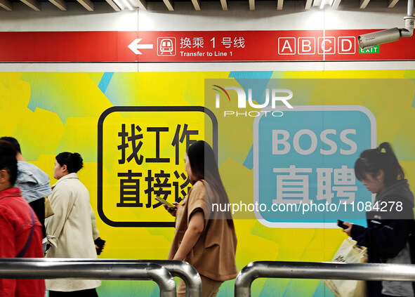 Passengers are walking past a light box advertising ''looking for jobs'' at Dawanglu Metro station in Beijing, China, on March 17, 2024. 