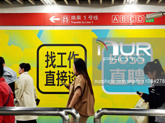 Passengers are walking past a light box advertising ''looking for jobs'' at Dawanglu Metro station in Beijing, China, on March 17, 2024. (