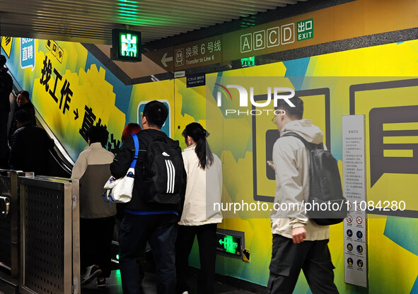 Passengers are walking past a light box advertising ''looking for jobs'' at Dawanglu Metro station in Beijing, China, on March 17, 2024. 