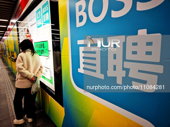 Passengers are walking past a light box advertising ''looking for jobs'' at Dawanglu Metro station in Beijing, China, on March 17, 2024. 