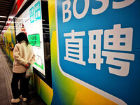 Passengers are walking past a light box advertising ''looking for jobs'' at Dawanglu Metro station in Beijing, China, on March 17, 2024. (