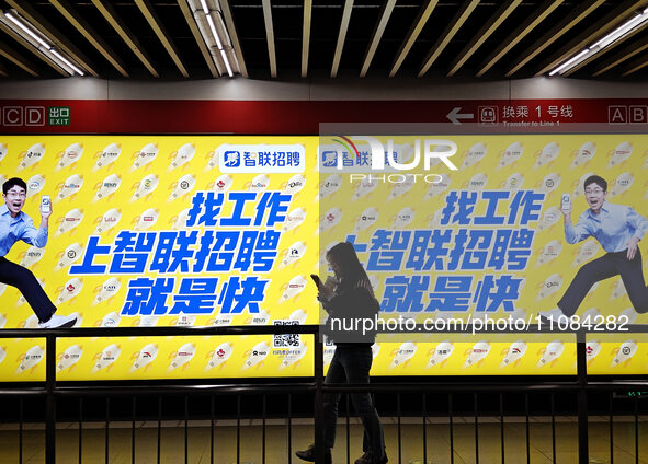 Passengers are walking past a light box advertising ''looking for jobs'' at Dawanglu Metro station in Beijing, China, on March 17, 2024. 