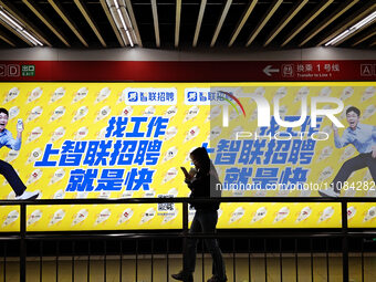 Passengers are walking past a light box advertising ''looking for jobs'' at Dawanglu Metro station in Beijing, China, on March 17, 2024. (