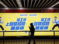 Passengers are walking past a light box advertising ''looking for jobs'' at Dawanglu Metro station in Beijing, China, on March 17, 2024. (