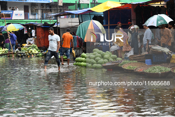 A vegetable vendor is waiting for customers in a waterlogged market at Karwan Bazar in Dhaka, Bangladesh, on March 19, 2024, after heavy mon...