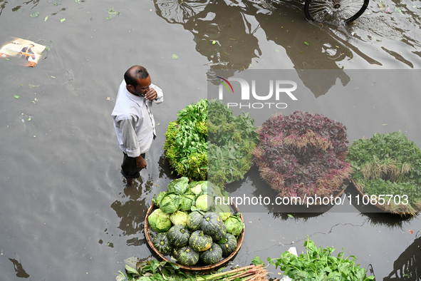 A vegetable vendor is waiting for customers in a waterlogged market at Karwan Bazar in Dhaka, Bangladesh, on March 19, 2024, after heavy mon...