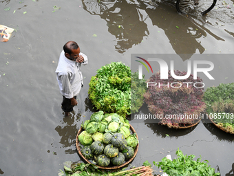 A vegetable vendor is waiting for customers in a waterlogged market at Karwan Bazar in Dhaka, Bangladesh, on March 19, 2024, after heavy mon...