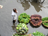 A vegetable vendor is waiting for customers in a waterlogged market at Karwan Bazar in Dhaka, Bangladesh, on March 19, 2024, after heavy mon...