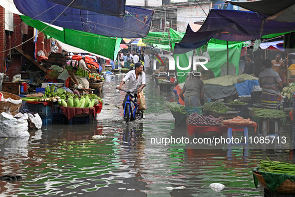 A vegetable vendor is waiting for customers in a waterlogged market at Karwan Bazar in Dhaka, Bangladesh, on March 19, 2024, after heavy mon...