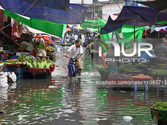 A vegetable vendor is waiting for customers in a waterlogged market at Karwan Bazar in Dhaka, Bangladesh, on March 19, 2024, after heavy mon...