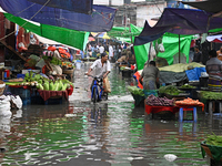 A vegetable vendor is waiting for customers in a waterlogged market at Karwan Bazar in Dhaka, Bangladesh, on March 19, 2024, after heavy mon...