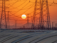 High-voltage power lines and potato greenhouses are being seen at sunset in Tengzhou, China, on March 20, 2024. (