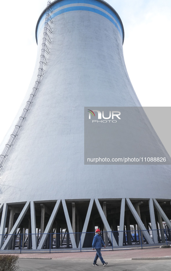 A power plant worker is walking by a cool water tower, which has achieved zero discharge of circulating water, in Zouping, Shandong province...