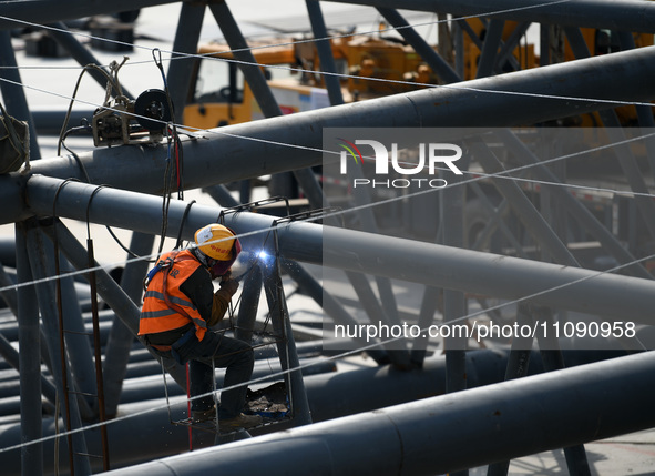 Construction workers are assembling steel structure roof trusses at the east station of Lushan Station of the Anjiu Section of the Beijing-H...