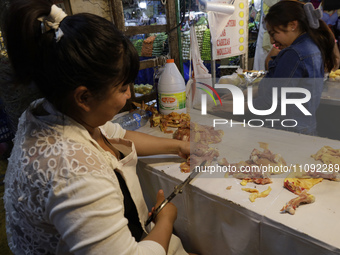 A woman is cutting chicken into pieces for sale at a market in Mexico City. Recently, the Ministry of Health of Tlaxcala in Mexico issued an...