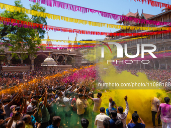 Thousands of devotees are cheering as a priest sprays colored powder and water on them during the celebrations of the colorful Holi festival...