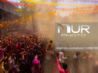 Thousands of devotees are cheering as a priest sprays colored powder and water on them during the celebrations of the colorful Holi festival...