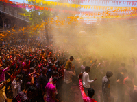 Thousands of devotees are cheering as a priest sprays colored powder and water on them during the celebrations of the colorful Holi festival...