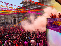 Thousands of devotees are cheering as a priest sprays colored powder and water on them during the celebrations of the colorful Holi festival...