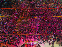 Thousands of devotees are cheering as a priest sprays colored powder and water on them during the celebrations of the colorful Holi festival...