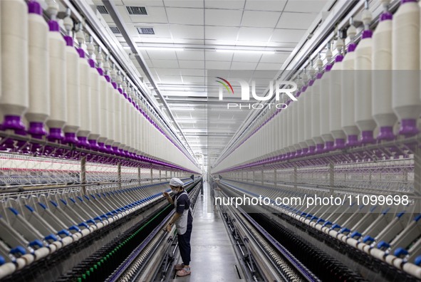 A worker is operating an intelligent production line at a textile company in Taizhou, Jiangsu Province, China, on March 26, 2024. 