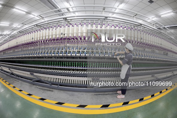 A worker is operating an intelligent production line at a textile company in Taizhou, Jiangsu Province, China, on March 26, 2024. 