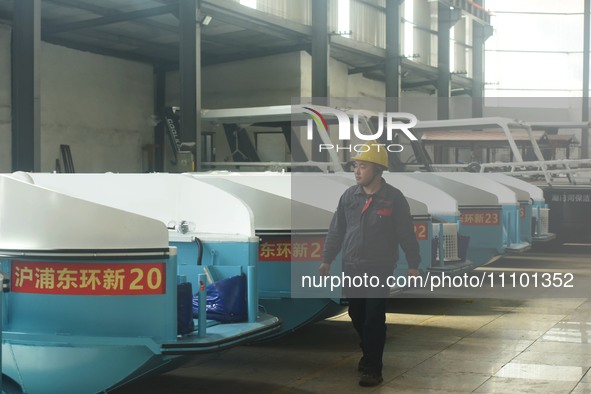 A worker is inspecting the self-developed water surface cleaning long arm environmental protection ship at a shipping company's factory buil...