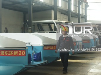 A worker is inspecting the self-developed water surface cleaning long arm environmental protection ship at a shipping company's factory buil...