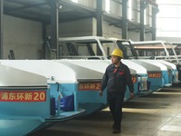 A worker is inspecting the self-developed water surface cleaning long arm environmental protection ship at a shipping company's factory buil...