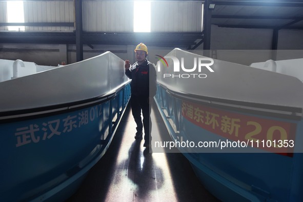 A worker is inspecting the self-developed water surface cleaning long arm environmental protection ship at a shipping company's factory buil...